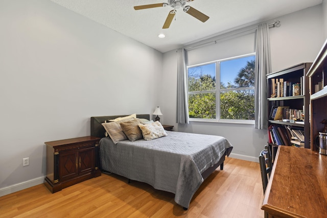 bedroom with ceiling fan, baseboards, and light wood-style floors