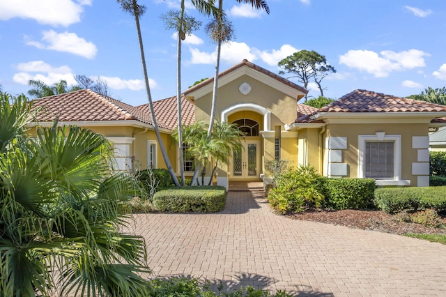 mediterranean / spanish house with a tile roof, french doors, and stucco siding