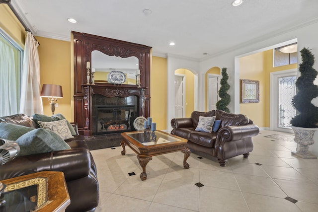 living area featuring a glass covered fireplace, light tile patterned flooring, arched walkways, and ornamental molding