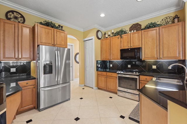 kitchen with dark countertops, light tile patterned floors, appliances with stainless steel finishes, and a sink