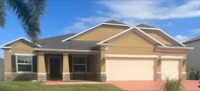 view of front of home featuring a garage, a front yard, and stucco siding