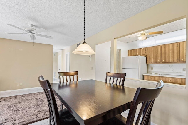 dining space with a textured ceiling, ceiling fan, light tile patterned floors, and baseboards