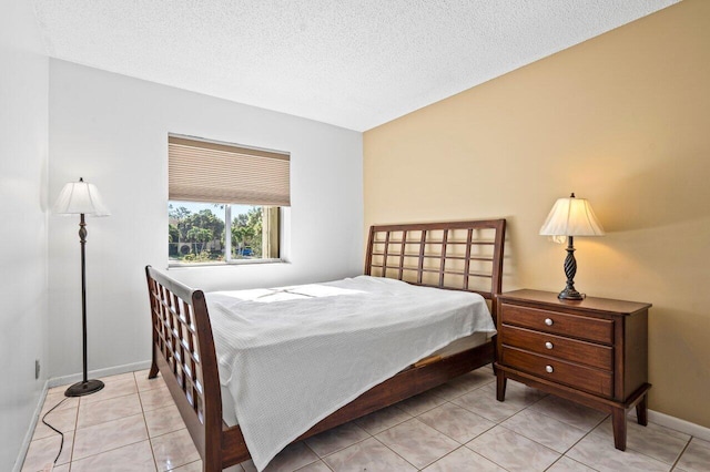 bedroom with light tile patterned flooring, a textured ceiling, and baseboards