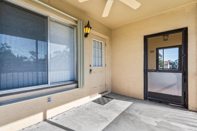 entrance to property featuring a ceiling fan and stucco siding