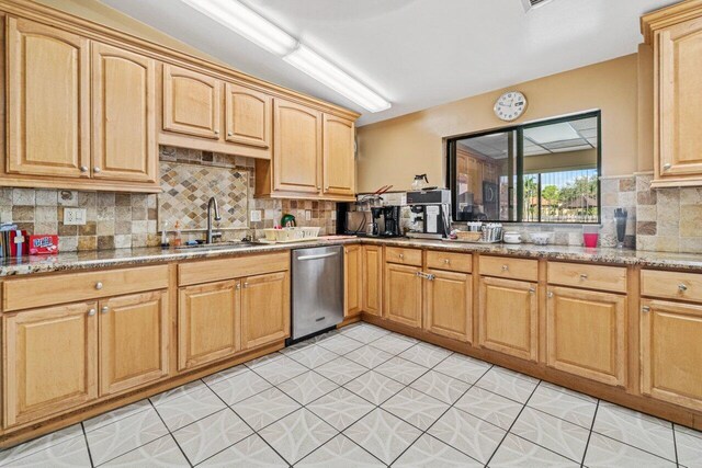 kitchen featuring light stone counters, decorative backsplash, light brown cabinets, a sink, and dishwasher