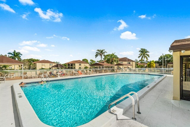 community pool with a patio and fence