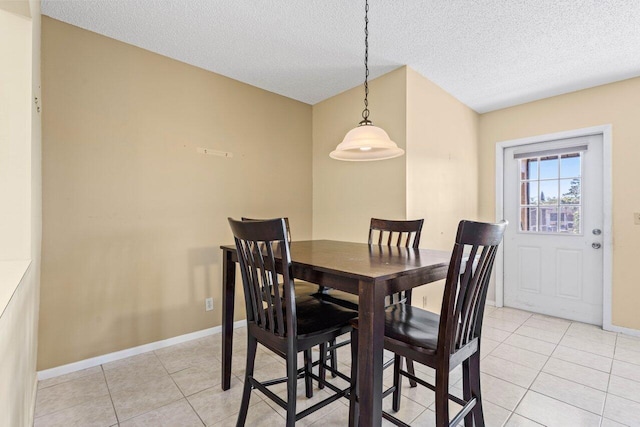 dining space with a textured ceiling, baseboards, and light tile patterned floors