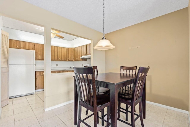 dining space with a ceiling fan, a textured ceiling, baseboards, and light tile patterned floors