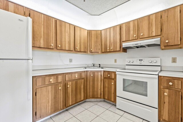 kitchen featuring light tile patterned floors, white appliances, light countertops, under cabinet range hood, and a sink