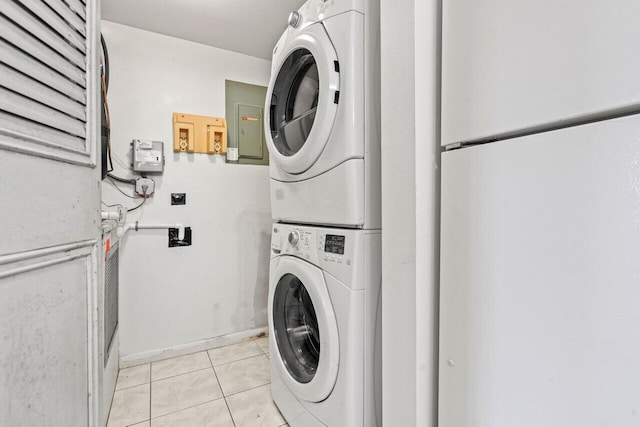 laundry area featuring laundry area, stacked washing maching and dryer, light tile patterned flooring, and electric panel