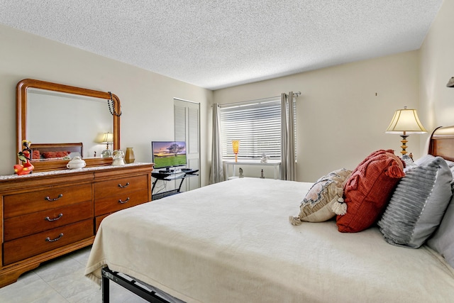 bedroom featuring a textured ceiling, light tile patterned floors, and a closet