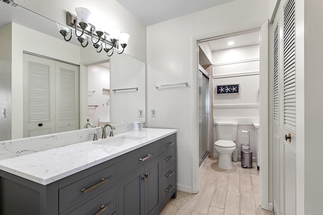 full bath with a closet, toilet, vanity, a shower stall, and wood finished floors