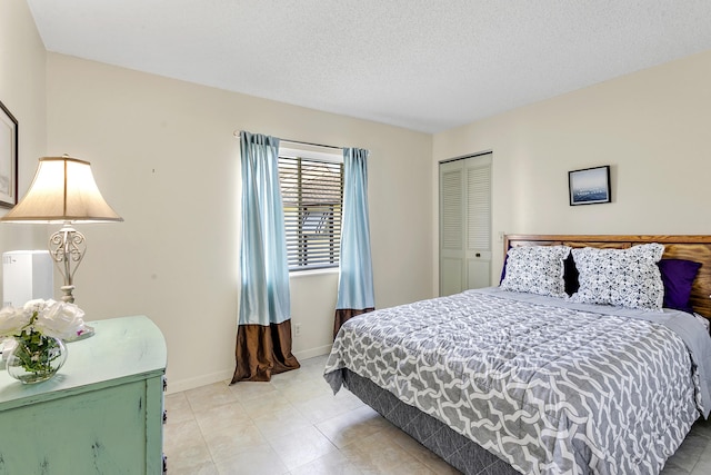 bedroom featuring a textured ceiling, baseboards, and a closet