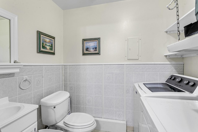 bathroom featuring toilet, vanity, tile walls, electric panel, and washer and clothes dryer