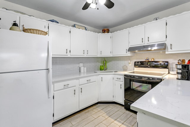 kitchen with range with electric cooktop, decorative backsplash, freestanding refrigerator, under cabinet range hood, and a sink