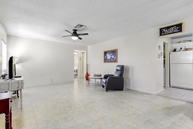 sitting room with a textured ceiling, baseboards, visible vents, and a ceiling fan