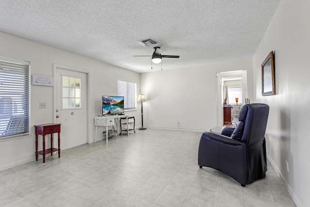 sitting room with visible vents, ceiling fan, a textured ceiling, and baseboards