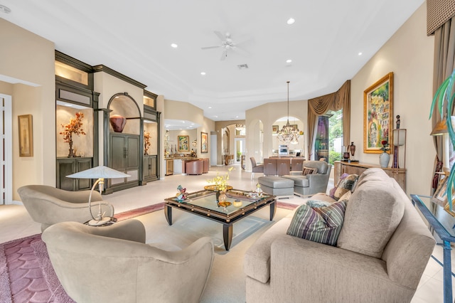 living area featuring arched walkways, tile patterned floors, recessed lighting, visible vents, and ceiling fan with notable chandelier