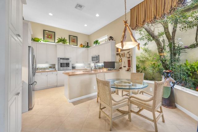 kitchen with visible vents, white cabinets, appliances with stainless steel finishes, a peninsula, and hanging light fixtures