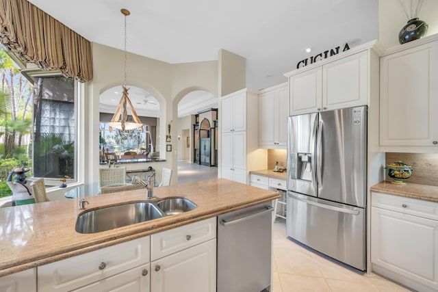 kitchen with light tile patterned flooring, a sink, white cabinets, appliances with stainless steel finishes, and tasteful backsplash