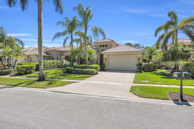 mediterranean / spanish-style home with a garage, decorative driveway, a front lawn, and stucco siding