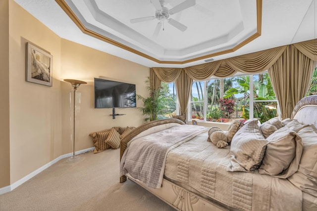 carpeted bedroom with a ceiling fan, a raised ceiling, and baseboards