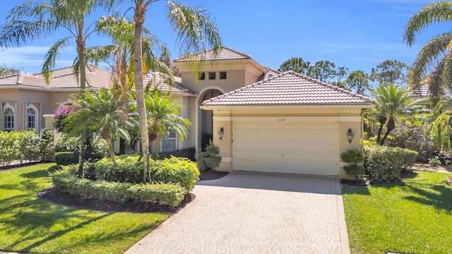 mediterranean / spanish home with a garage, a front lawn, decorative driveway, and stucco siding