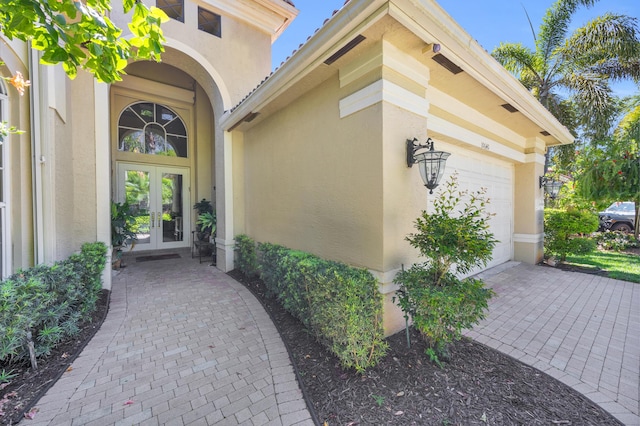 property entrance featuring an attached garage, stucco siding, and french doors