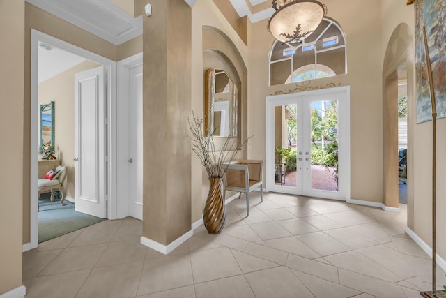 foyer entrance with arched walkways, french doors, light tile patterned floors, a high ceiling, and baseboards