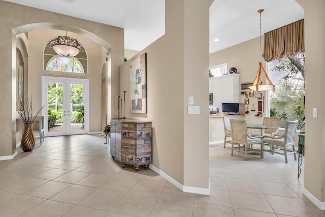 foyer with french doors, a towering ceiling, and light tile patterned floors