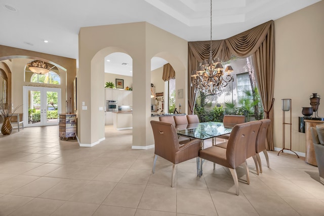 dining space featuring light tile patterned floors, baseboards, arched walkways, an inviting chandelier, and french doors