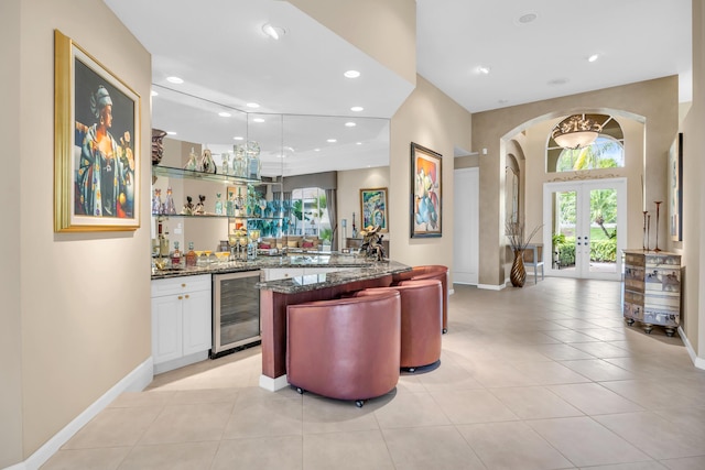 bar with light tile patterned floors, beverage cooler, wet bar, french doors, and recessed lighting