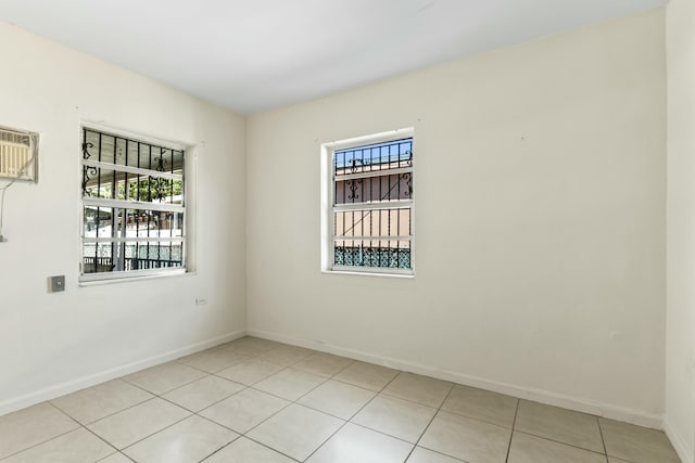 spare room featuring an AC wall unit, light tile patterned floors, and baseboards