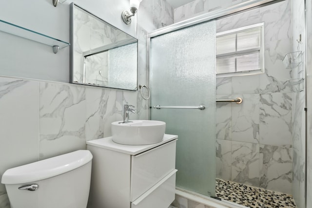 full bath featuring vanity, tile walls, toilet, and a marble finish shower