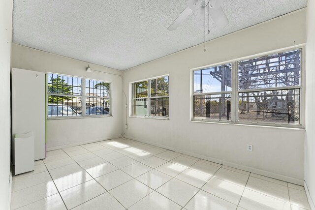 unfurnished room with tile patterned floors, a textured ceiling, and a ceiling fan