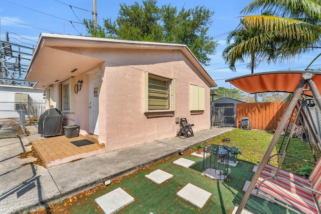 back of property featuring fence, stucco siding, a lawn, a patio, and a gate