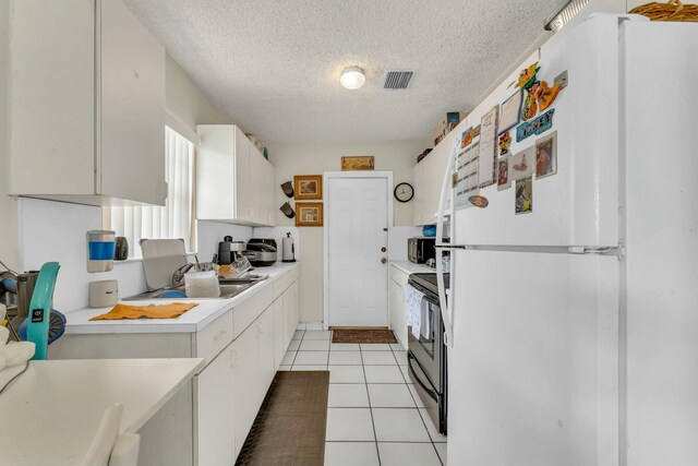 kitchen with visible vents, light countertops, freestanding refrigerator, electric range, and a sink