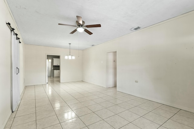 unfurnished room with light tile patterned floors, visible vents, ceiling fan with notable chandelier, and a barn door