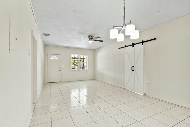 interior space featuring light tile patterned floors, a barn door, visible vents, and ceiling fan with notable chandelier