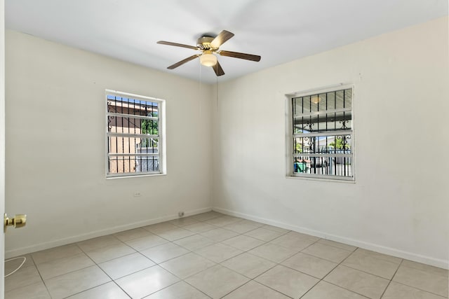 tiled spare room with baseboards and ceiling fan