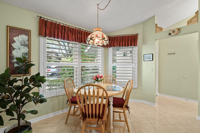 dining room with lofted ceiling, light tile patterned floors, baseboards, and a textured ceiling