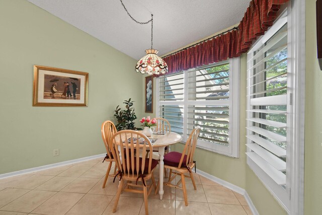 dining area featuring lofted ceiling, a textured ceiling, baseboards, and light tile patterned floors