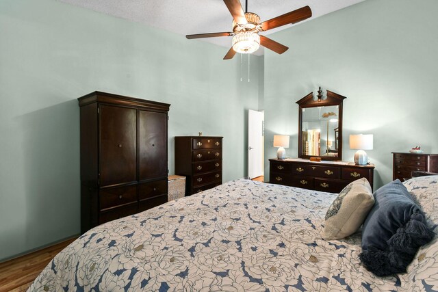 bedroom featuring ceiling fan, a high ceiling, and wood finished floors