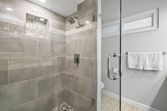 bathroom featuring toilet, a stall shower, and baseboards