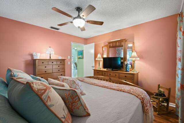 bedroom featuring a ceiling fan, visible vents, a textured ceiling, and wood finished floors