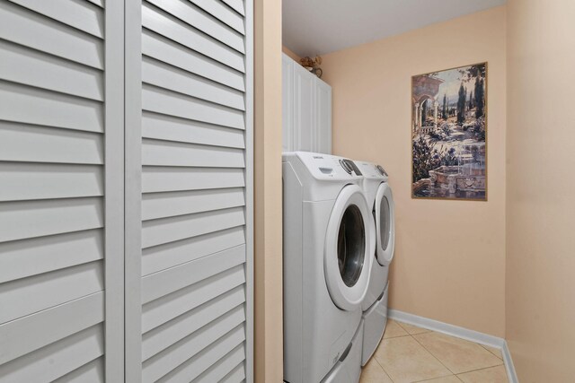 laundry room with cabinet space, baseboards, washer and clothes dryer, and light tile patterned flooring