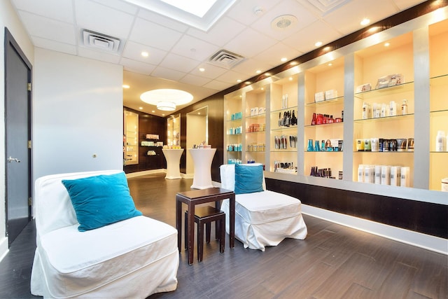 living area featuring built in shelves, wood finished floors, and visible vents