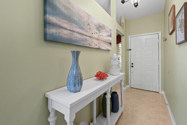 entryway with light tile patterned floors, baseboards, and a textured ceiling