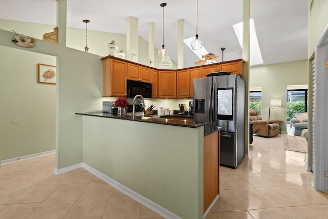 kitchen with light tile patterned floors, a peninsula, black microwave, stainless steel refrigerator with ice dispenser, and a sink