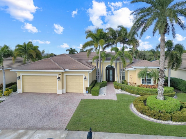 view of front of house with decorative driveway, a tile roof, stucco siding, a garage, and a front lawn